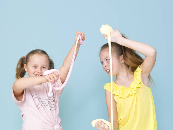 Две красивые маленькие девочки играют с самодельной слизью и весело проводят время в студии
  - Фото, изображение
