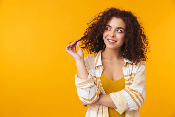 Image of adorable woman 20s touching her curly hair and looking  - Foto, afbeelding