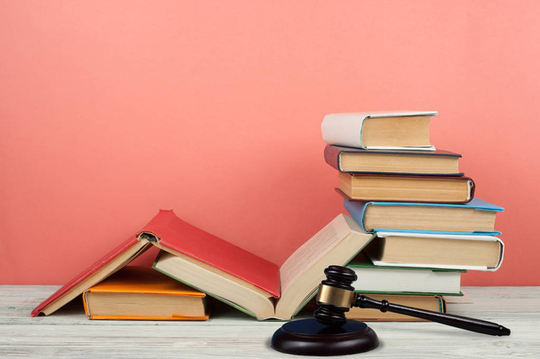 Law concept open book with wooden judges gavel on table in a courtroom or law enforcement office, pink background. Copy space for text - Photo, image