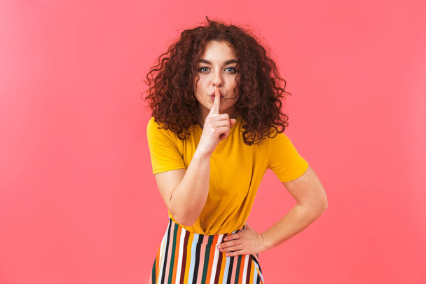 Cute beautiful young curly girl posing isolated over red wall background showing silence gesture. - Foto, Bild