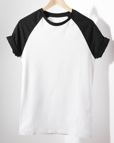 Εμπρόσθια όψη της αμερικανικής Χίπστερς ρετρό κλασικό tshirt ρούχα. Κενό πρότυπο vintage t-shirt κρέμονται σε κρεμάστρα σε άσπρο φόντο. Κινηματογράφηση σε πρώτο πλάνο. - Φωτογραφία, εικόνα