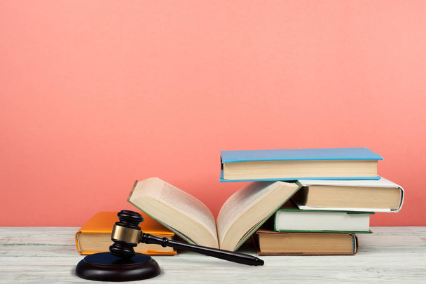 Law concept open book with wooden judges gavel on table in a courtroom or law enforcement office, pink background. Copy space for text - Fotó, kép