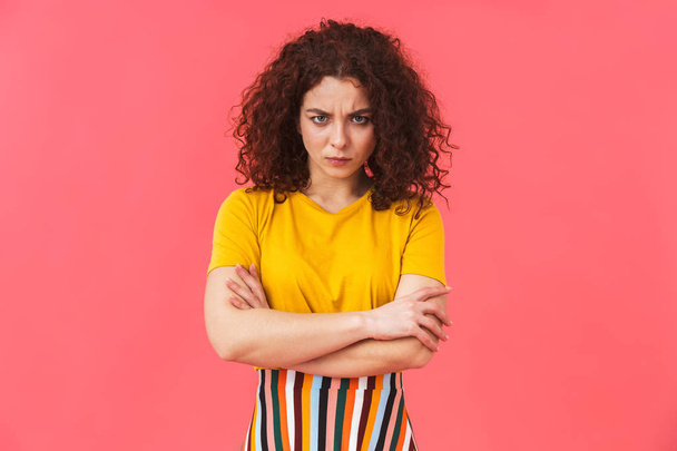 Displeased angry beautiful young curly girl posing isolated over red wall background. - Fotografie, Obrázek