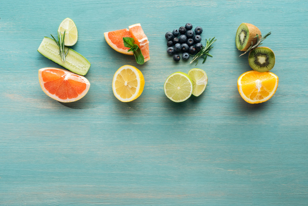 Vista superior de frutas cortadas y arándanos en superficie texturizada azul
 - Foto, imagen