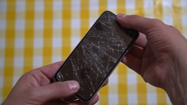 壊れた画面でスマートフォンの概念。分解表示で携帯電話を保持している男の手のトップビュー。現代の携帯電話で破壊され粉砕されたlcdタッチスクリーン。ガジェットは修理が必要だ - 映像、動画