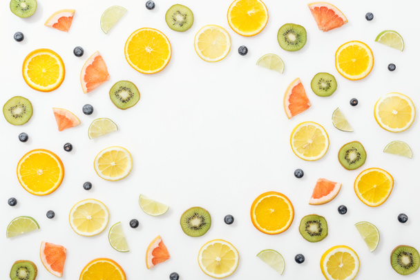 Top view of cut fruits and blueberries on white surface - Foto, afbeelding