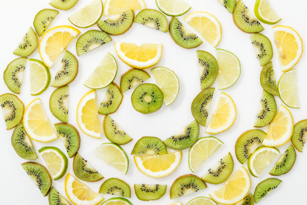 Posa piatta con limoni tagliati, lime e kiwi su superficie bianca
 - Foto, immagini