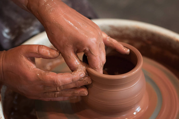 Roue de potier rotative et ustensiles d'argile sur elle prise d'en haut. Un sculpte ses mains avec une tasse d'argile sur une roue de potier. Mains dans l'argile
.  - Photo, image
