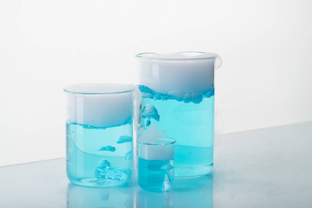 Different size beakers with blue liquid and dry ice. Sublimation of dry ice.  - Photo, Image
