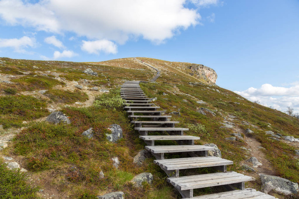 Stairs rise up to the mountain. Beautiful blue sky and clouds. Lapland. - Zdjęcie, obraz