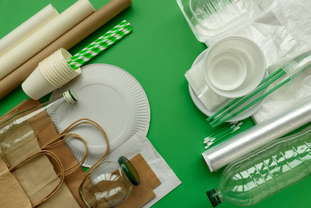 Plastic, paper and glass packages on green background. Copy space. Top view. Eco and save earth concept. - Zdjęcie, obraz