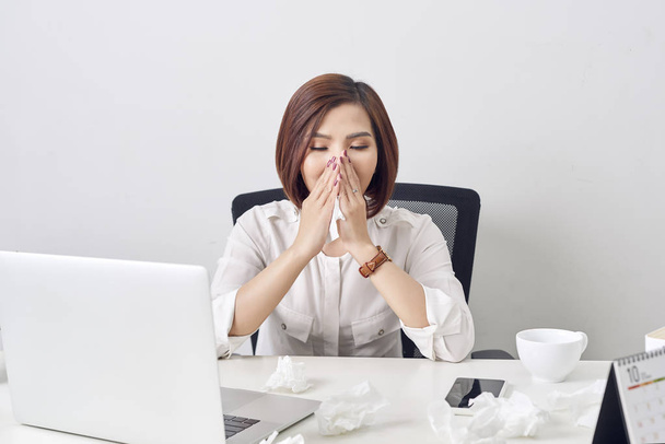 Грустная измученная женщина с тканями, страдающими от холода во время работы с ноутбуком за столом
 - Фото, изображение