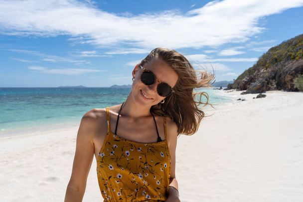 Ευτυχισμένη γυναίκα χαμογελά και διασκεδάζει στην παραλία. - Φωτογραφία, εικόνα