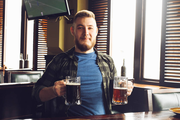 guy with beard with two mugs of beer in pub - Photo, Image