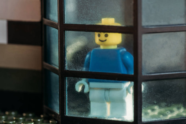 KYIV, UKRAINE - MARCH 15, 2019: lego figurine with smiley face looking through window in block house - Фото, изображение