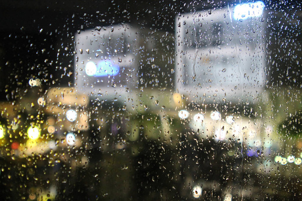 Яскраві розмиті вогні на мокрій склянці вікна в дощову ніч
 - Фото, зображення