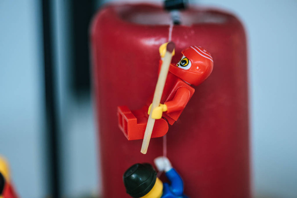 KYIV, UKRAINE - MARCH 15, 2019: close up view of plastic red lego figurine with match climbing candle with rope - Photo, image