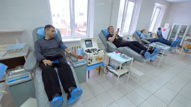 Los donantes se sientan en sillas médicas, bombeando sangre en un centro de transfusión
. - Metraje, vídeo