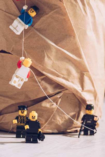 KYIV, UKRAINE - MARCH 15, 2019: lego policemen standing with weapon while plastic lego figurines climbing rope  - Foto, immagini