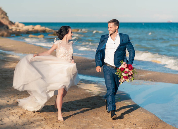 Düğün çifti, gelin ve damat deniz kenarında gelinlik giymişler. - Fotoğraf, Görsel