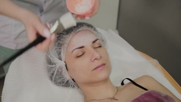 Wykwalifikowanej kosmetolog stawia maska na twarz kobiety leżącej w pomieszczeniu salon spa. - Materiał filmowy, wideo