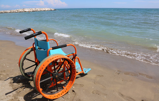 special orange wheel chair on the beach - Photo, Image