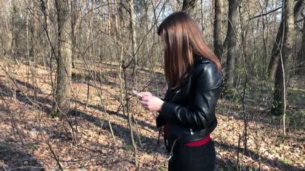 Nainen etsii puhelinsignaalia metsästä.
 - Materiaali, video