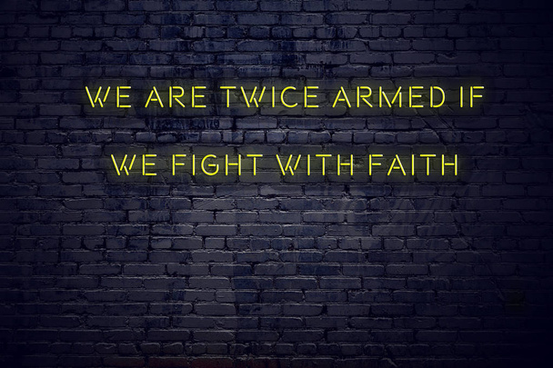 我々 は信仰と戦う場合武装している 2 回のレンガの壁にネオンサインに肯定的な感動の引用 - 写真・画像