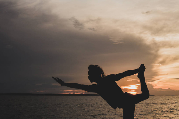 Egy ember gyakorlatok jóga testtartás, naplementekor. A háttérben fekete folyó, az Amazonas, Brazília. - Fotó, kép