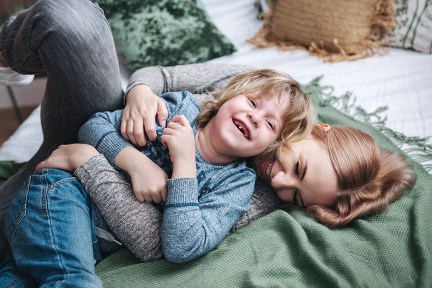 Playful family. Mother and baby son laughing in bed - Valokuva, kuva
