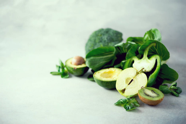 Organic green vegetables and fruits on grey background. Copy space. Green apple, lettuce, cucumber, avocado, kale, lime, kiwi, grapes, banana, broccoli - Fotoğraf, Görsel