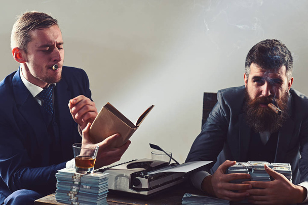 Feeling relaxed. Successful investment in business. Businessmen write financial report while drinking and smoking. Business partners with cash money. Money brokers counting profit increase - 写真・画像