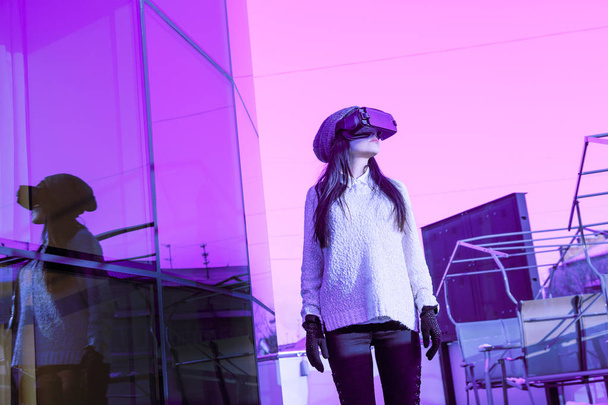 VR ροζ μωβ μπλε κορίτσι πρόσωπο γυναίκας εικονικής πραγματικότητας ακουστικά μελαχρινή τηλέφωνο φουτουριστικό βιολετί ουρανό έπιπλα χειμώνα - Φωτογραφία, εικόνα