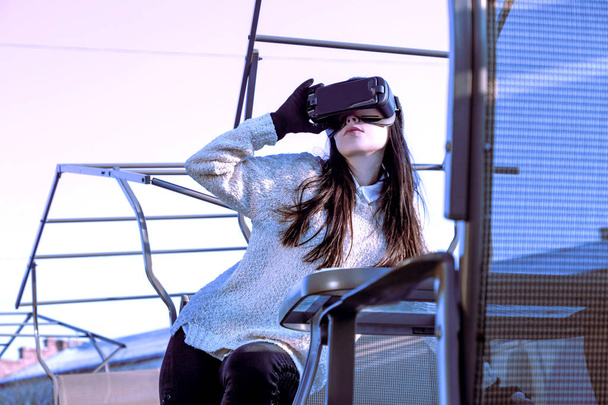 VR rózsaszín, lila, kék lány arca nő virtuális valóság fejhallgató barna telefon futurisztikus lila ég bútor téli - Fotó, kép