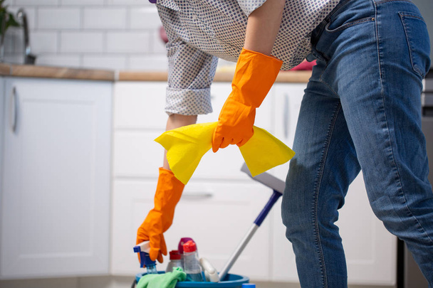 Female housekeeper while cleaning office. Woman wearing protective gloves near bucket full of cleaning supplies - Foto, imagen