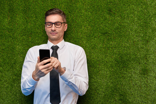 Businessman using smartphone on lawn - Zdjęcie, obraz