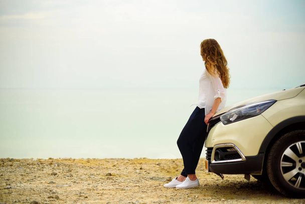 View of young woman traveler looking at sea sunset, sitting on hatchback car with the copy space. - Fotografie, Obrázek