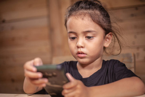 un chico llevar camiseta negra viendo su móvil en la habitación de madera
 - Foto, imagen