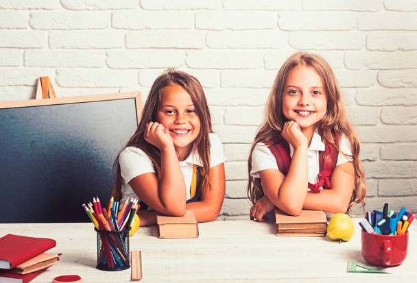 Back to school and home schooling. Happy school kids at lesson in september 1. Little girls eat apple at lunch break. Friendship of small sisters in classroom at knowledge day. School time of girls - Фото, изображение