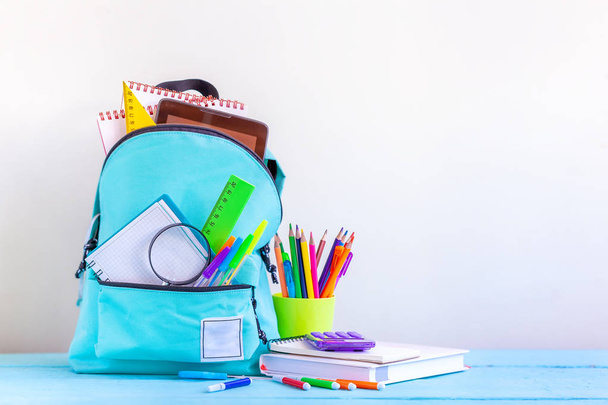 Full turquoise School Backpack with stationery on table. - Valokuva, kuva