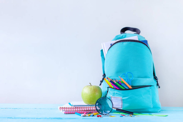 Full turquoise School Backpack with stationery on table. - Φωτογραφία, εικόνα