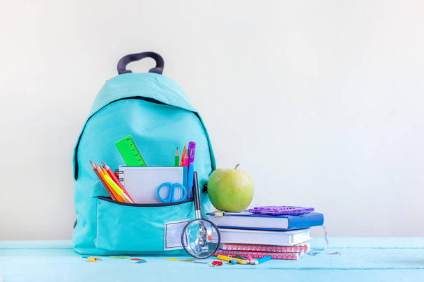 Full turquoise School Backpack with stationery on table. - Foto, afbeelding