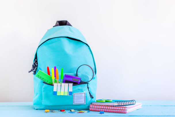 Full turquoise School Backpack with stationery on table. - Φωτογραφία, εικόνα