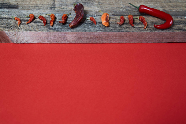 Dried chili pepper lying on wooden boards on a red background Image. Close up. - Φωτογραφία, εικόνα