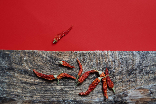 Dried chili pepper lying on wooden boards on a red background Image. Close up. - Φωτογραφία, εικόνα