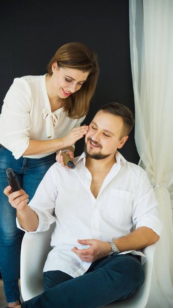 Skin care. Beautiful woman applies moisturizer on the face of a smiling man. Protection and skin care. - Photo, Image