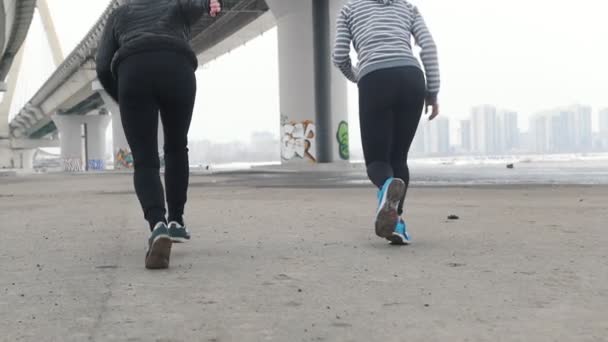 zwei athletische Frauen laufen unter der Brücke - Filmmaterial, Video