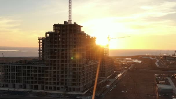 Luchtfoto bouw van meerdere verdiepingen gebouw met bouw kranen bij zonsondergang - Video