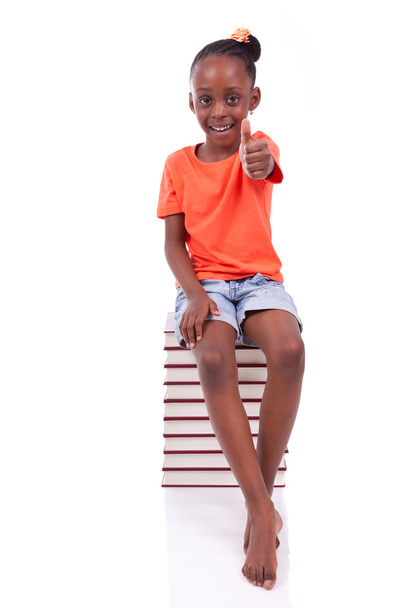 Cute black african american little girl seated in a stack of boo - Foto, Imagen