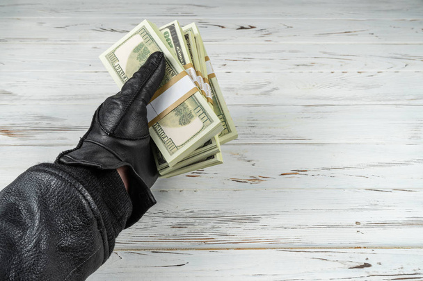 Εγκληματική αντίληψη άνθρωπος με μαύρα δερμάτινα γάντια κρατώντας τούβλα των χρημάτων - Φωτογραφία, εικόνα